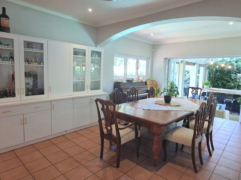 Spacious dining room featuring built-in cabinetry, terracotta floor tiles, and an elegant archway leading to an outdoor patio area through bi-fold doors.