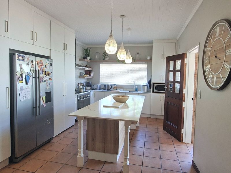 A well-appointed kitchen featuring extensive built-in cabinetry, a central island with stone countertop, stainless steel appliances, and durable tiled flooring.