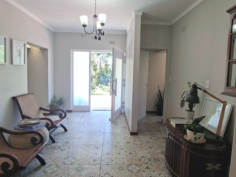 Welcoming entrance hall featuring decorative patterned floor tiles, beadboard ceiling, and a bright glass-paneled front door leading to the exterior.