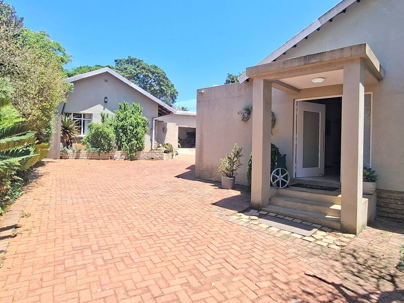 Front exterior view of the property featuring a brick paved driveway leading to a covered entrance porch with concrete steps.