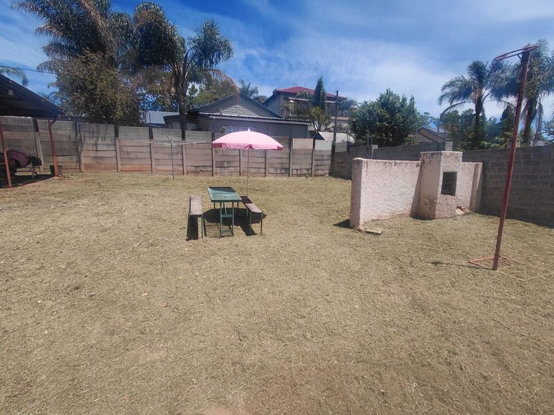 Spacious backyard featuring a precast concrete boundary wall, a built-in braai area, and ample open space for landscaping potential.