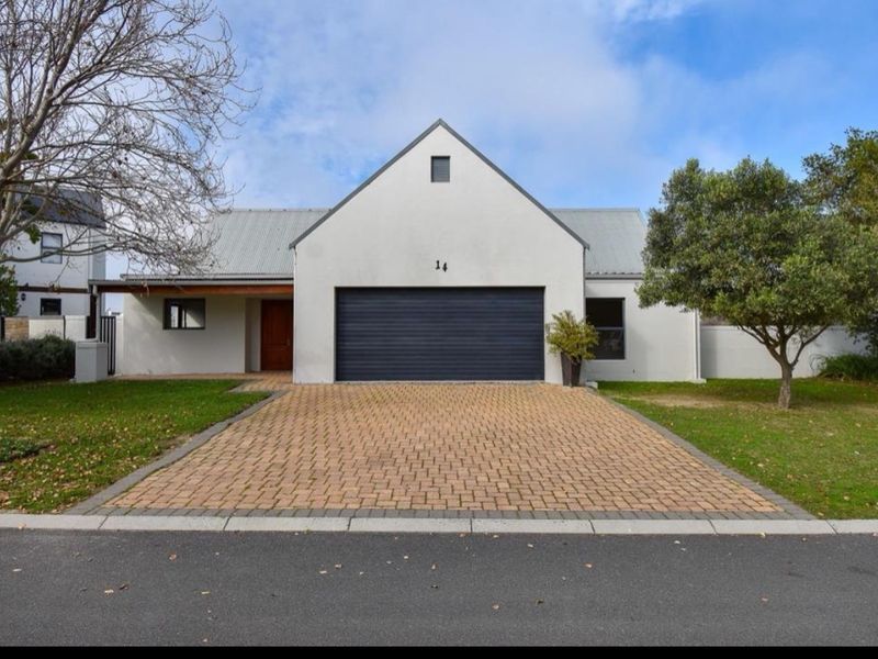 Front elevation of a modern house featuring a paved driveway, double garage, and a well-maintained garden.