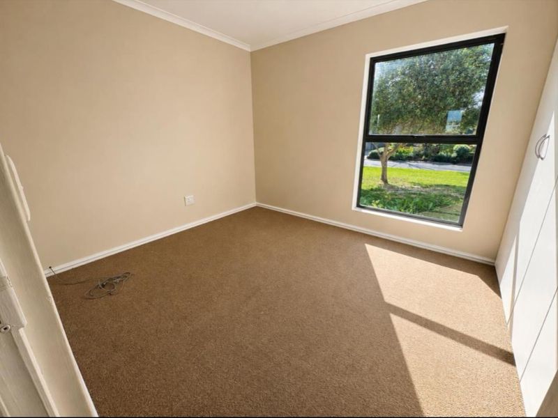 A vacant bedroom featuring neutral wall tones, carpeted flooring, and a built-in wardrobe with natural light from the window.