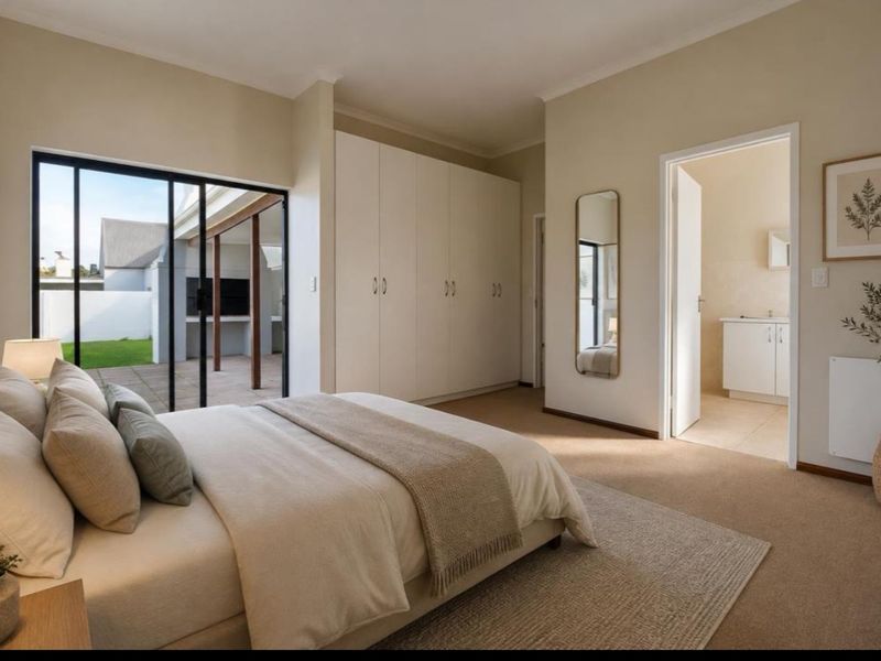 Spacious bedroom featuring built-in cupboards, carpeted flooring, and sliding glass doors leading to an outdoor patio, with an adjoining en-suite bathroom.