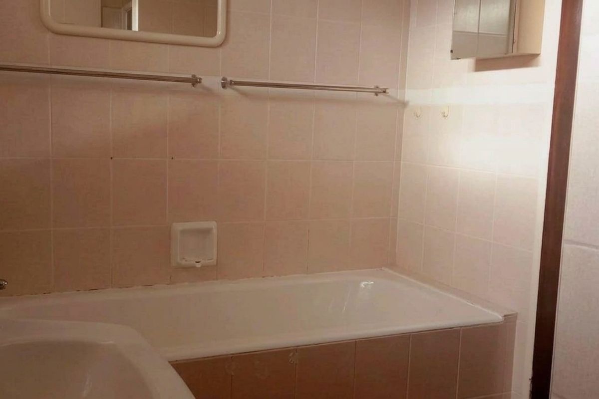 A functional bathroom featuring a built-in bathtub with a wall-mounted shower head and tiled wall finishes.