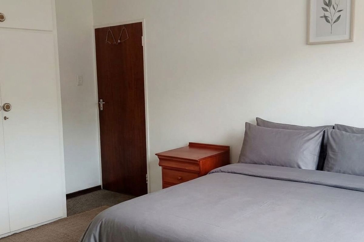 A functional bedroom featuring built-in cupboards and carpeted flooring, providing a clean and neutral space.