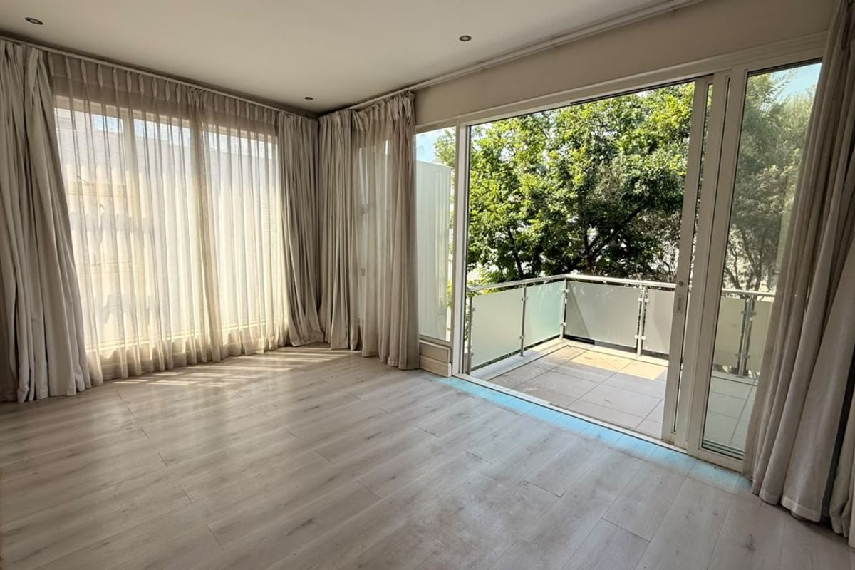 Bright and spacious living area featuring light laminate flooring, recessed lighting, and large sliding glass doors opening onto a private balcony.