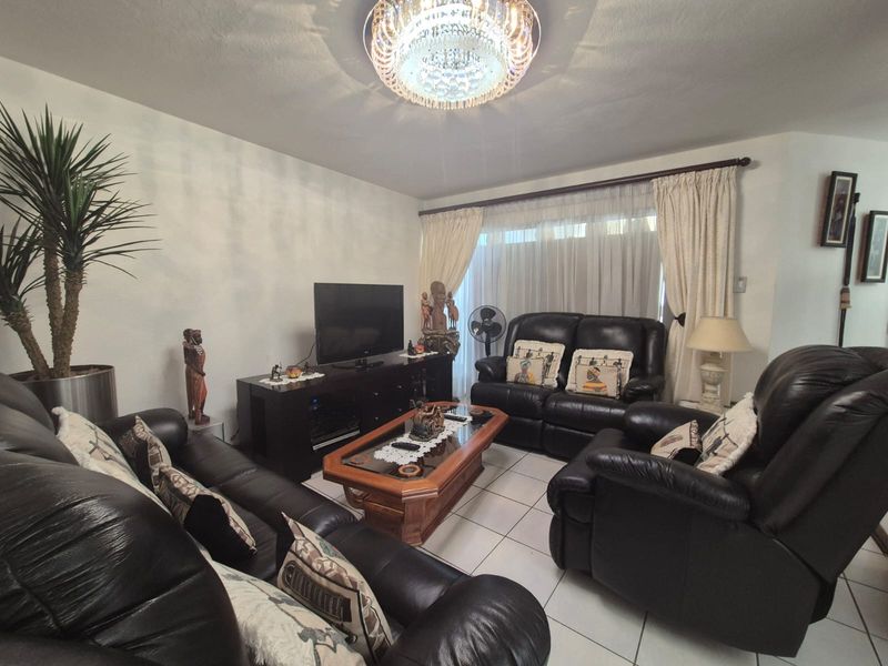 A comfortable living room featuring tiled flooring and a decorative crystal chandelier, providing a functional space for relaxation.