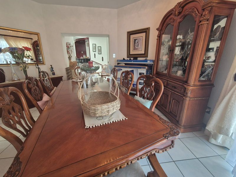 A formal dining room featuring tiled flooring and a view through to the adjacent living area.