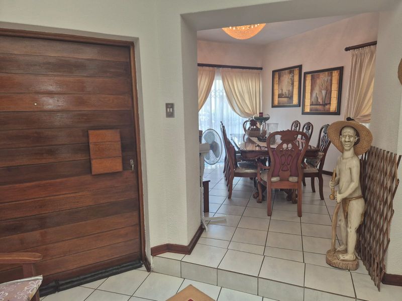 Dining area featuring tiled flooring and access to a patio through a sliding glass door, adjacent to the main entrance with a wooden door.