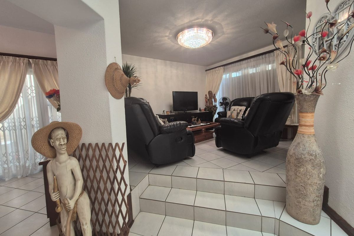 A sunken living room featuring tiled flooring, a central ceiling light fixture, and sliding glass doors leading to an outdoor area.