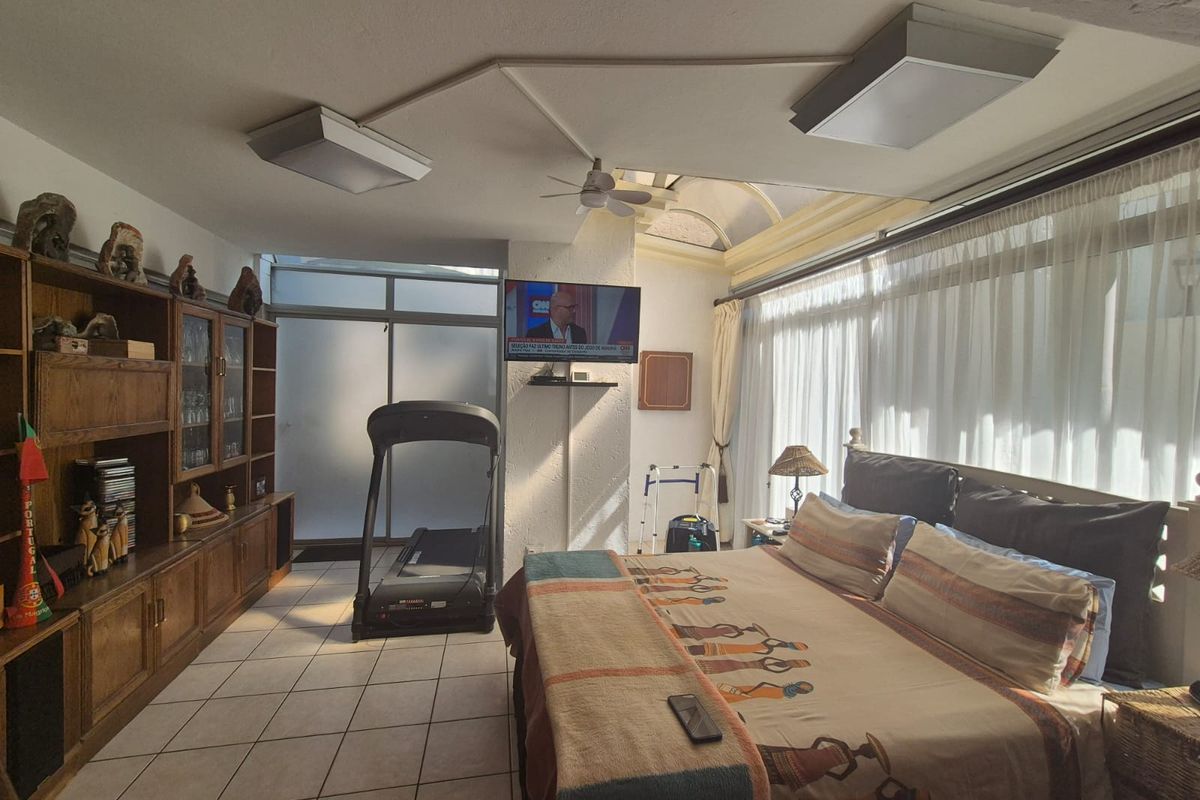 Spacious bedroom featuring tiled flooring, built-in cabinetry, a ceiling fan, and a skylight, offering a functional layout with natural light.