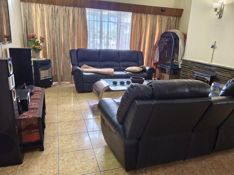 A living room featuring tiled flooring, a stone feature wall, and a built-in fireplace, offering a functional space for relaxation.