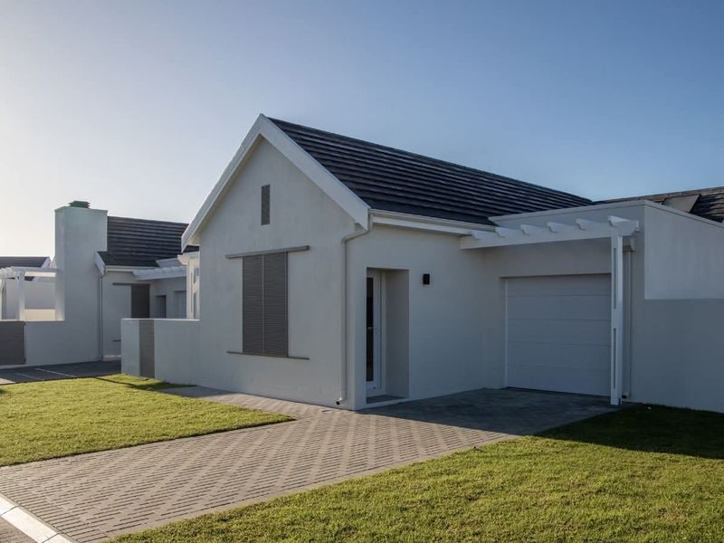 A modern single-story residential home featuring a tiled roof, paved driveway, integrated garage, and clean exterior finishes.