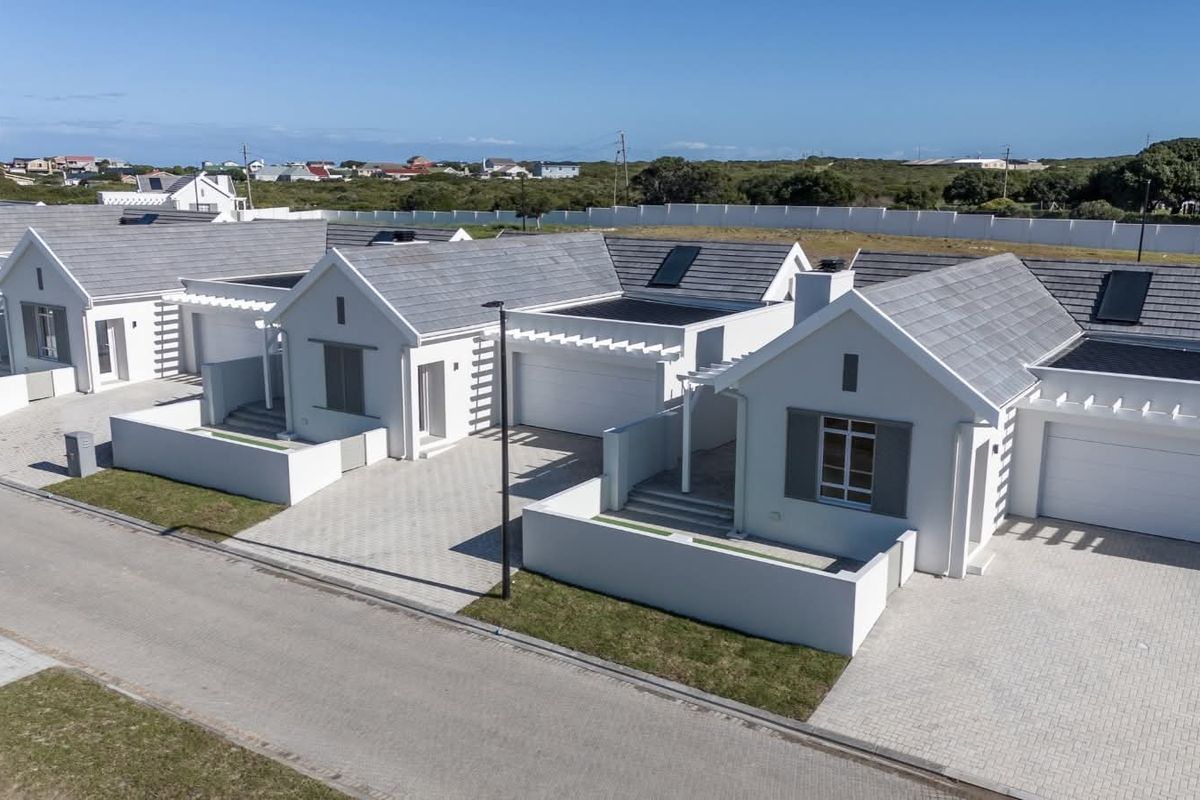 Aerial view of a modern residential estate featuring multiple houses with tiled roofs, solar panels, paved driveways, and private garages.