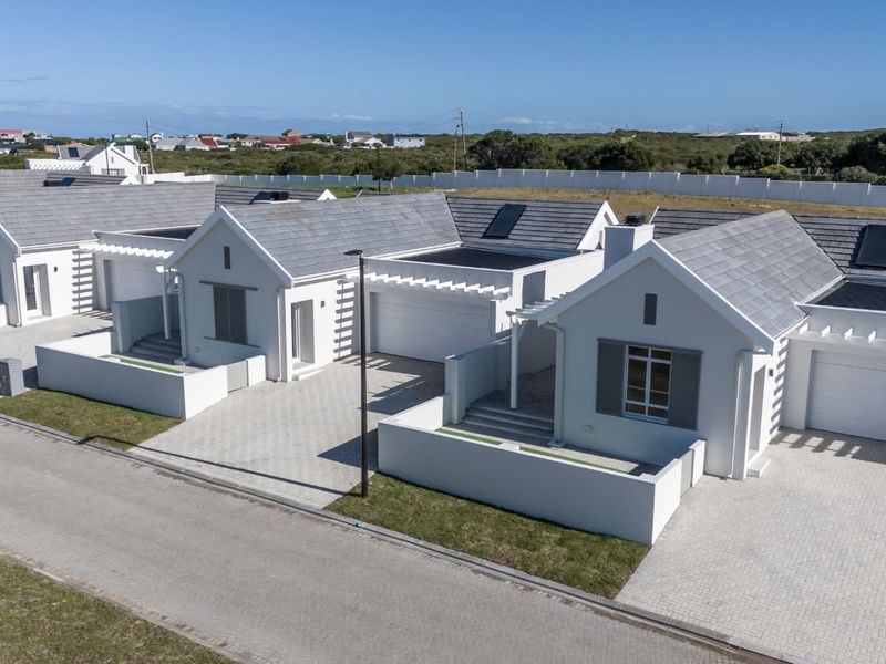 Aerial view of a modern residential estate featuring multiple houses with tiled roofs, solar panels, paved driveways, and private garages.
