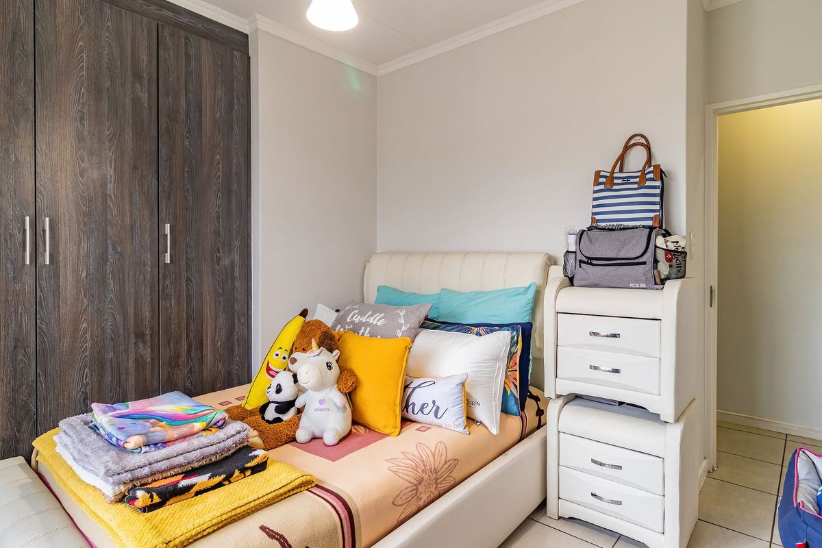 A well-maintained bedroom featuring built-in cupboards and tiled flooring, offering a functional and comfortable living space.