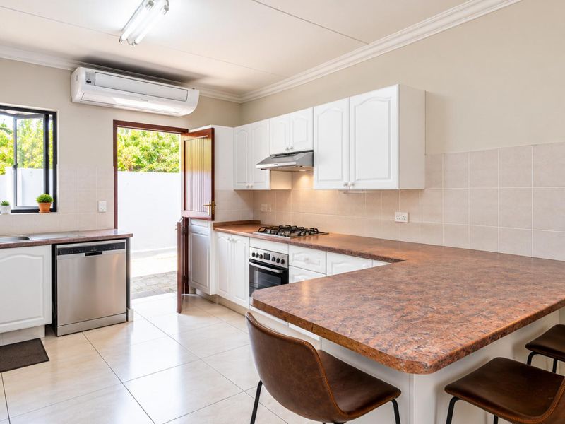 A functional kitchen featuring white cabinetry, laminate countertops, a gas hob, built-in oven, and direct access to an outdoor area.