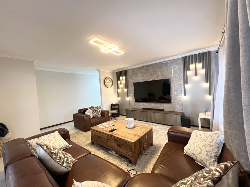 A well-appointed living room featuring a stylish marble-look feature wall with integrated lighting and a custom media console.