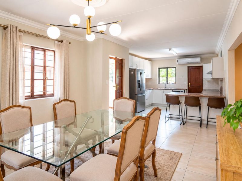 An open-plan dining and kitchen area featuring tiled floors, modern cabinetry, a breakfast bar, and a bright, well-maintained living space.