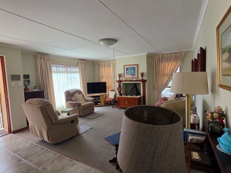 A comfortable living room featuring a fireplace, carpeted flooring, and direct access to an outdoor area through a security gate.