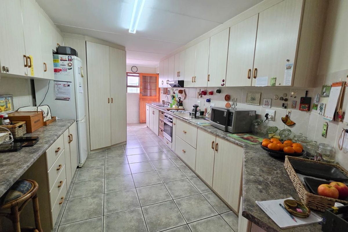 A functional galley-style kitchen featuring laminate cabinetry, tiled flooring, and a built-in oven with an extractor fan.
