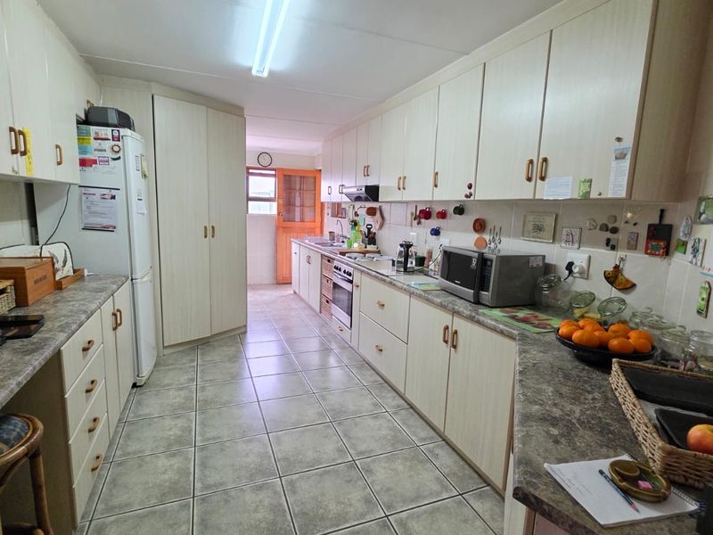 A functional galley-style kitchen featuring laminate cabinetry, tiled flooring, and a built-in oven with an extractor fan.