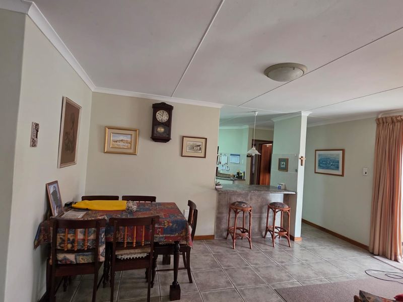 Open plan living and dining area featuring tiled flooring, a breakfast bar, and direct access to an outdoor space through a sliding glass door.