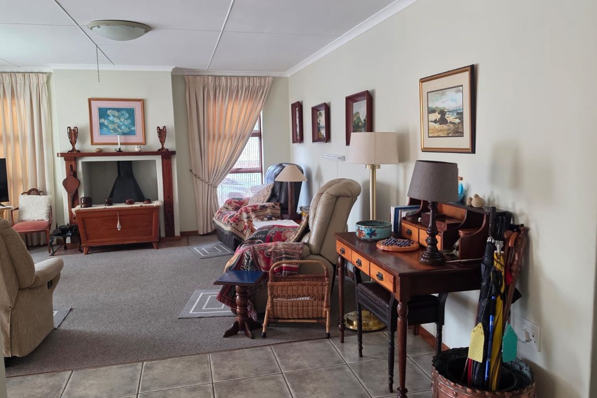 A spacious living room featuring a traditional fireplace with a mantelpiece, combining tiled and carpeted flooring with neutral wall finishes.
