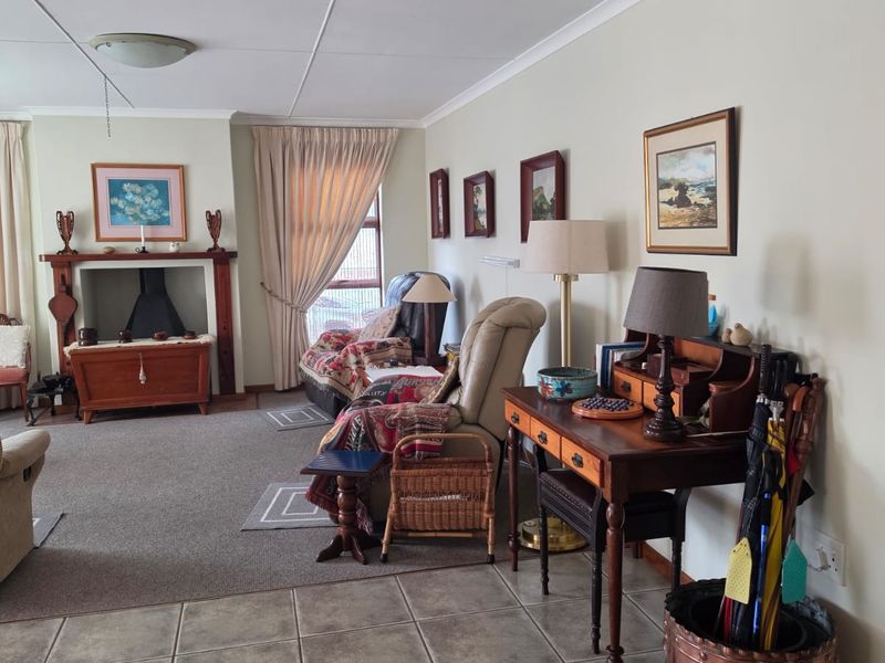 A spacious living room featuring a traditional fireplace with a mantelpiece, combining tiled and carpeted flooring with neutral wall finishes.