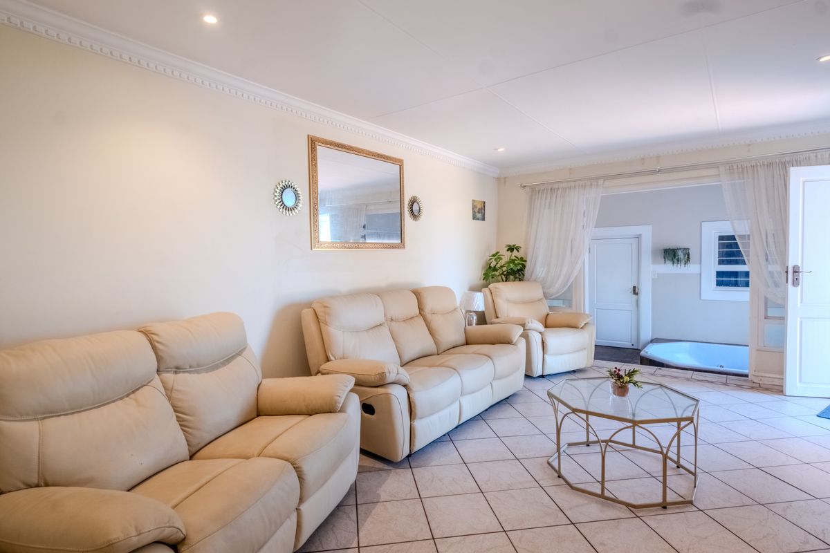 A bright and spacious living room featuring ceramic floor tiles, crown molding, and recessed downlights, with direct access to an adjacent area.