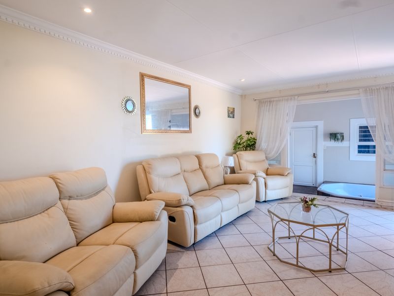 A bright and spacious living room featuring ceramic floor tiles, crown molding, and recessed downlights, with direct access to an adjacent area.
