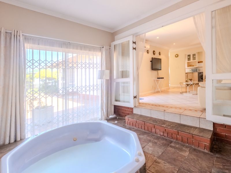 Open plan living area featuring a built-in jacuzzi, tiled flooring, and direct access to the exterior through secure french doors.