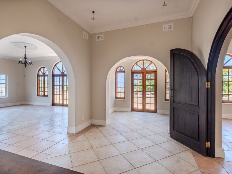 Spacious living area featuring elegant arched doorways, tiled flooring, and classic wooden framed windows that provide ample natural light.