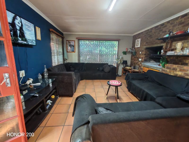 Spacious living room featuring a brick fireplace, terracotta tiled flooring, and security bars on windows, offering a functional and comfortable living space.