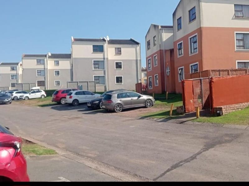 Exterior view of a multi-story apartment complex featuring paved parking areas and residential building facades.