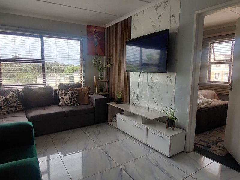 Living room featuring marble-effect floor tiles, a slatted wood accent wall, and a marble-effect media wall panel with integrated television.