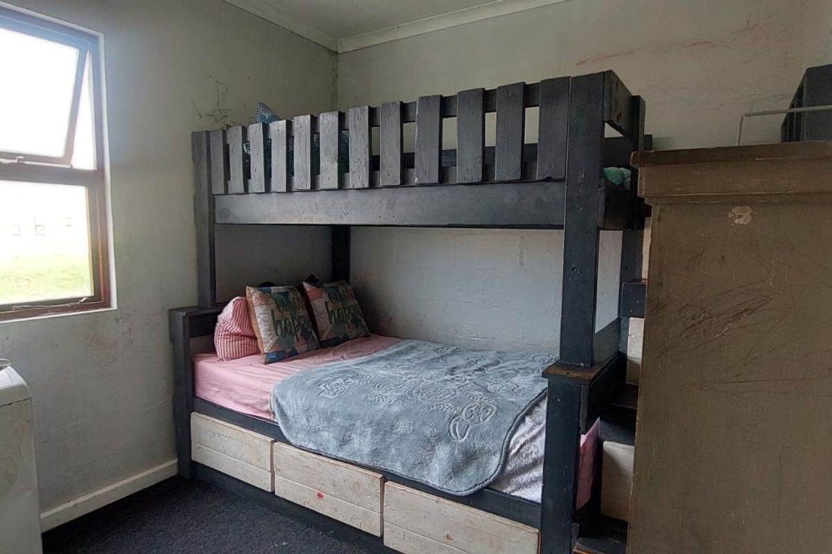 A bedroom featuring carpet flooring and a window, currently requiring cosmetic updates to the wall surfaces.