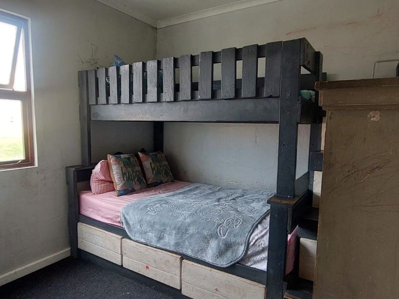 A bedroom featuring carpet flooring and a window, currently requiring cosmetic updates to the wall surfaces.