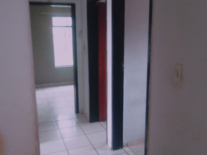 A simple interior hallway featuring tiled flooring and multiple doorways leading to adjacent rooms.