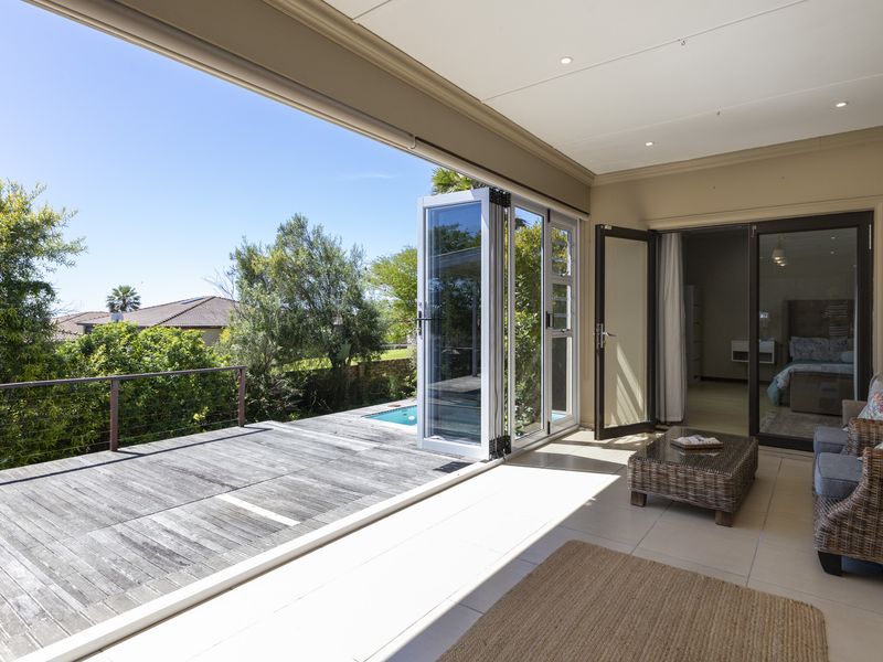 Covered patio featuring tiled flooring and bi-fold glass doors opening onto a timber deck with garden views.
