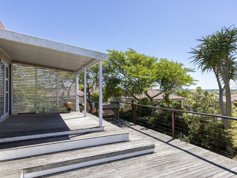 Spacious elevated timber deck featuring a covered patio area, slatted privacy screen, and wire balustrade, offering an ideal space for outdoor relaxation.