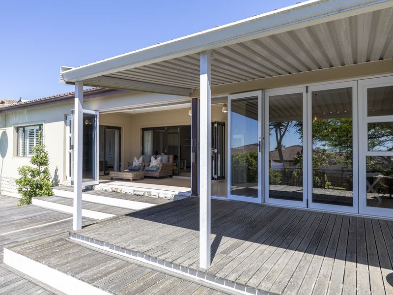 Spacious covered timber deck featuring bi-fold doors that provide seamless indoor-outdoor flow, overlooking the garden area.