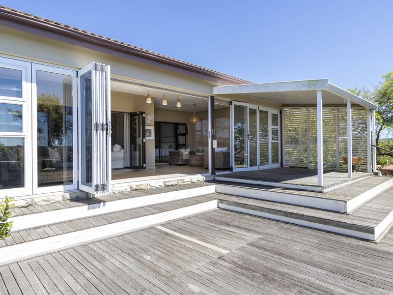Spacious outdoor timber deck featuring a covered patio area, bi-fold doors providing seamless indoor-outdoor flow, and a privacy screen.