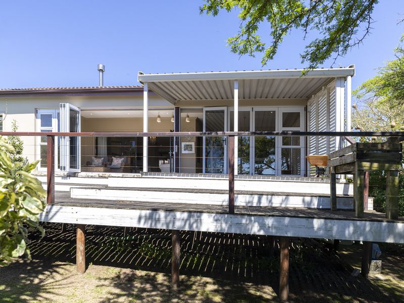 A raised timber deck with a covered patio area, featuring bi-fold doors leading into the home and a metal railing overlooking the garden.