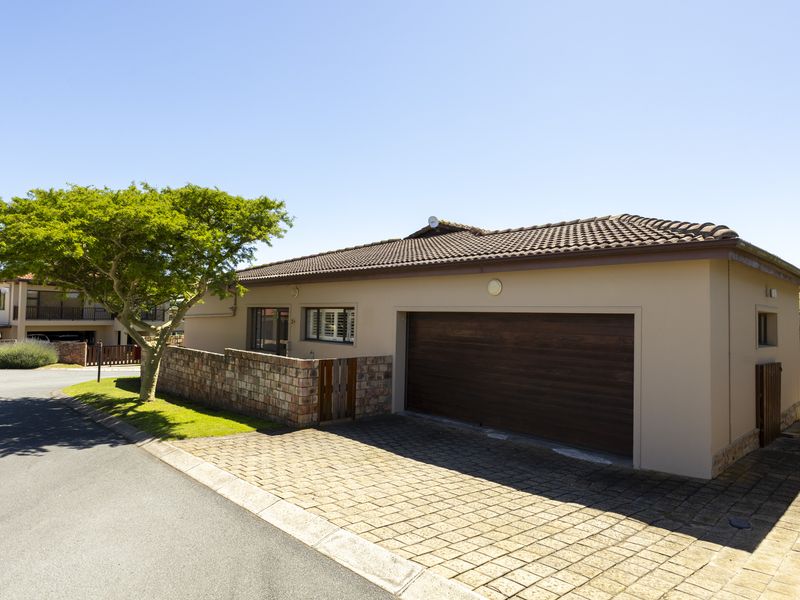 Front exterior view of the property featuring a paved driveway, a secure garage, and attractive stone wall detailing.