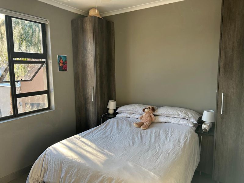 A functional bedroom featuring built-in cupboards and natural light from an aluminium-framed window.