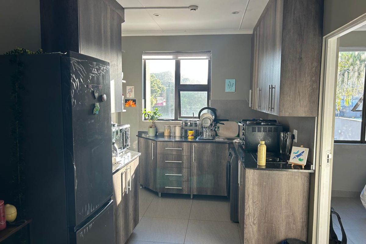 A functional kitchen featuring modern laminate cabinetry, granite countertops, tiled flooring, and integrated appliances, offering a clean and practical workspace.