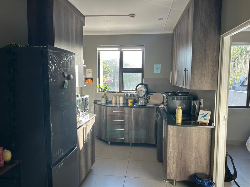 A functional kitchen featuring modern laminate cabinetry, granite countertops, tiled flooring, and integrated appliances, offering a clean and practical workspace.
