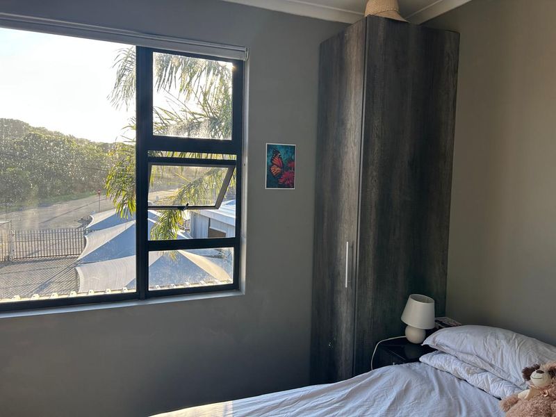 A bedroom featuring a built-in wardrobe and a large window with views of the surrounding area.